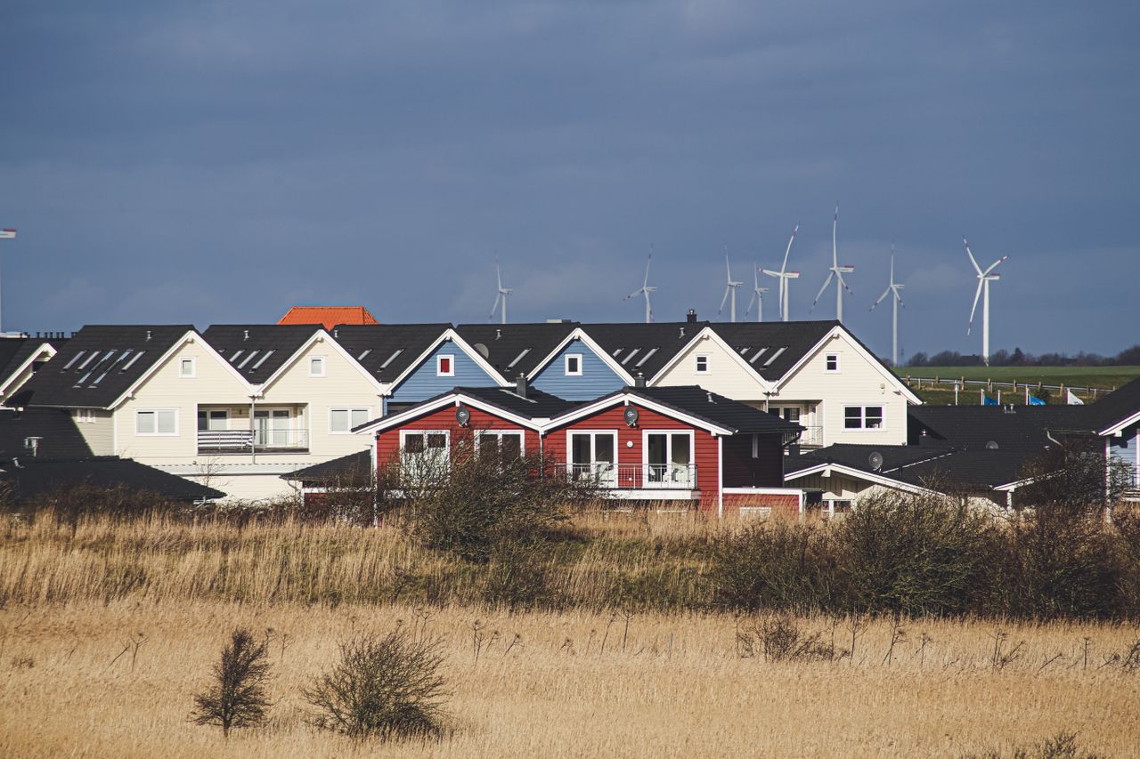 gallery-03 Charming rural houses with wind turbines in Dagebüll, Germany under cloudy skies.